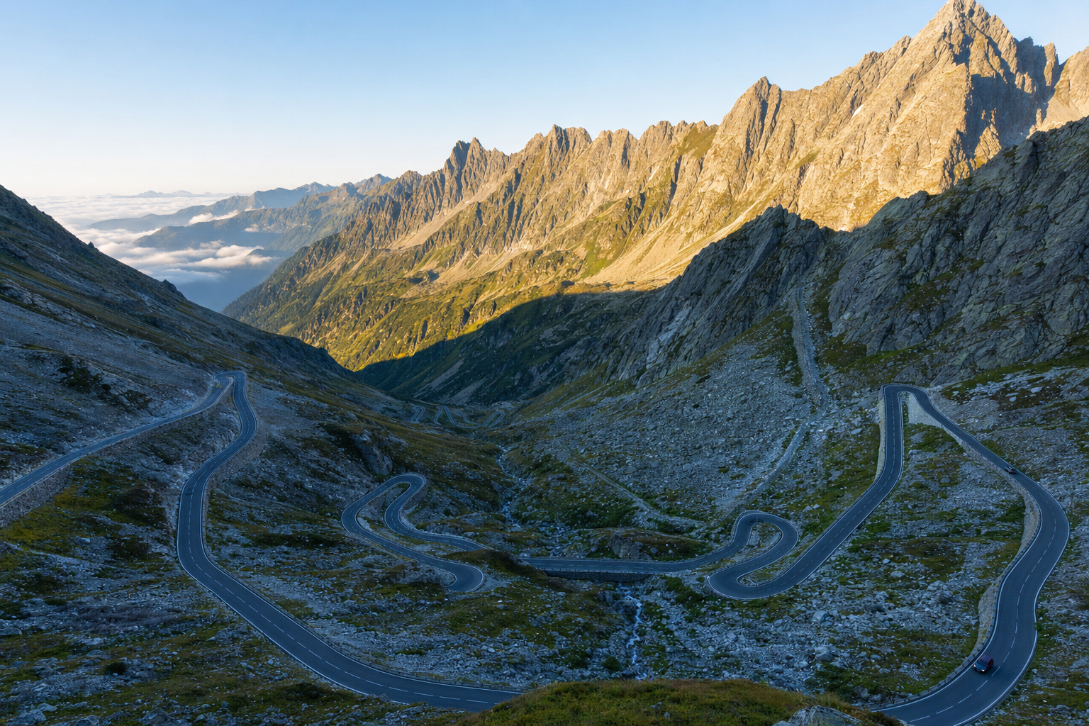 A winding mountain road navigating through a scenic, high-altitude alpine pass under clear skies.